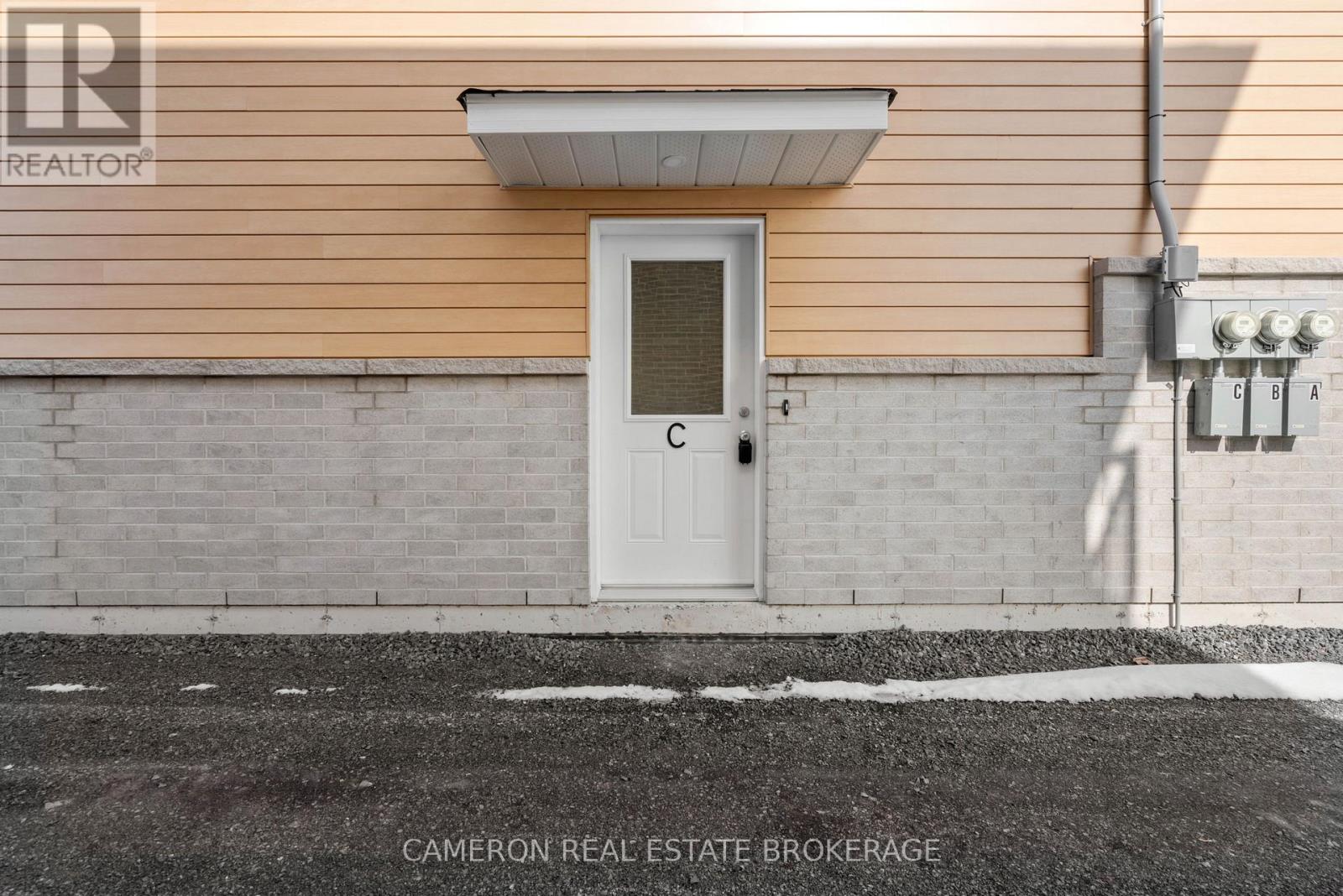 A white door is on the side of a building with a sign that says "Cameron Real Estate Brokerage.".