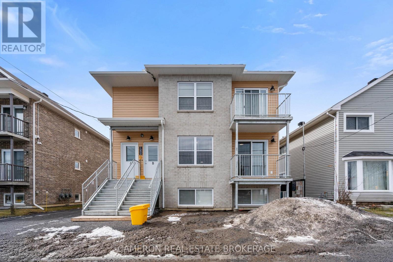 A real estate brokerage photo of a two-story townhouse with a balcony and a garage.