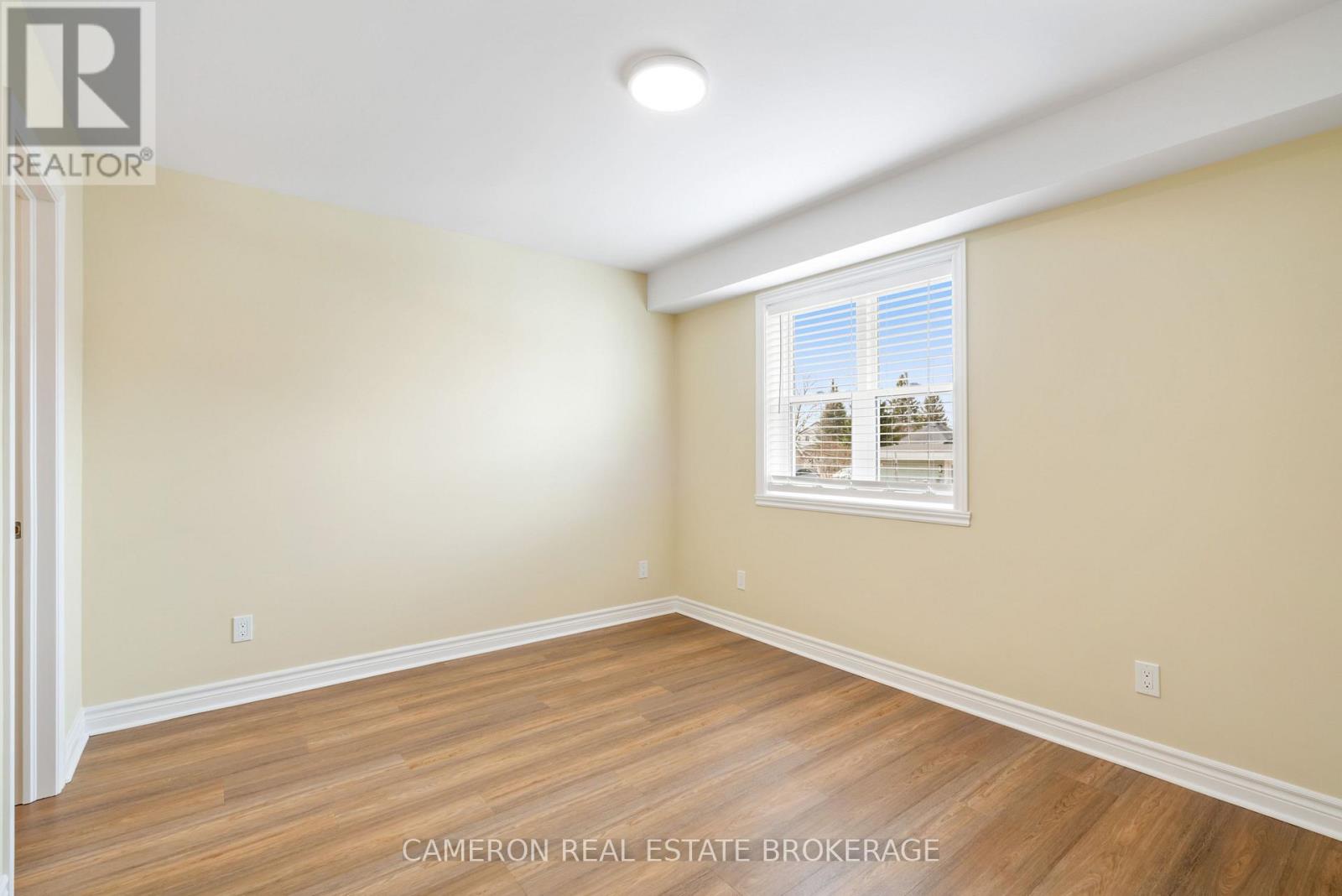 A room with wooden flooring and a window showing a view of a building.