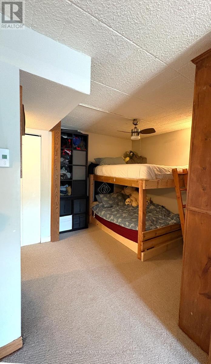 A bedroom with a bed, dresser, and ceiling fan.