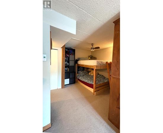 A bedroom with a bed, dresser, and ceiling fan.