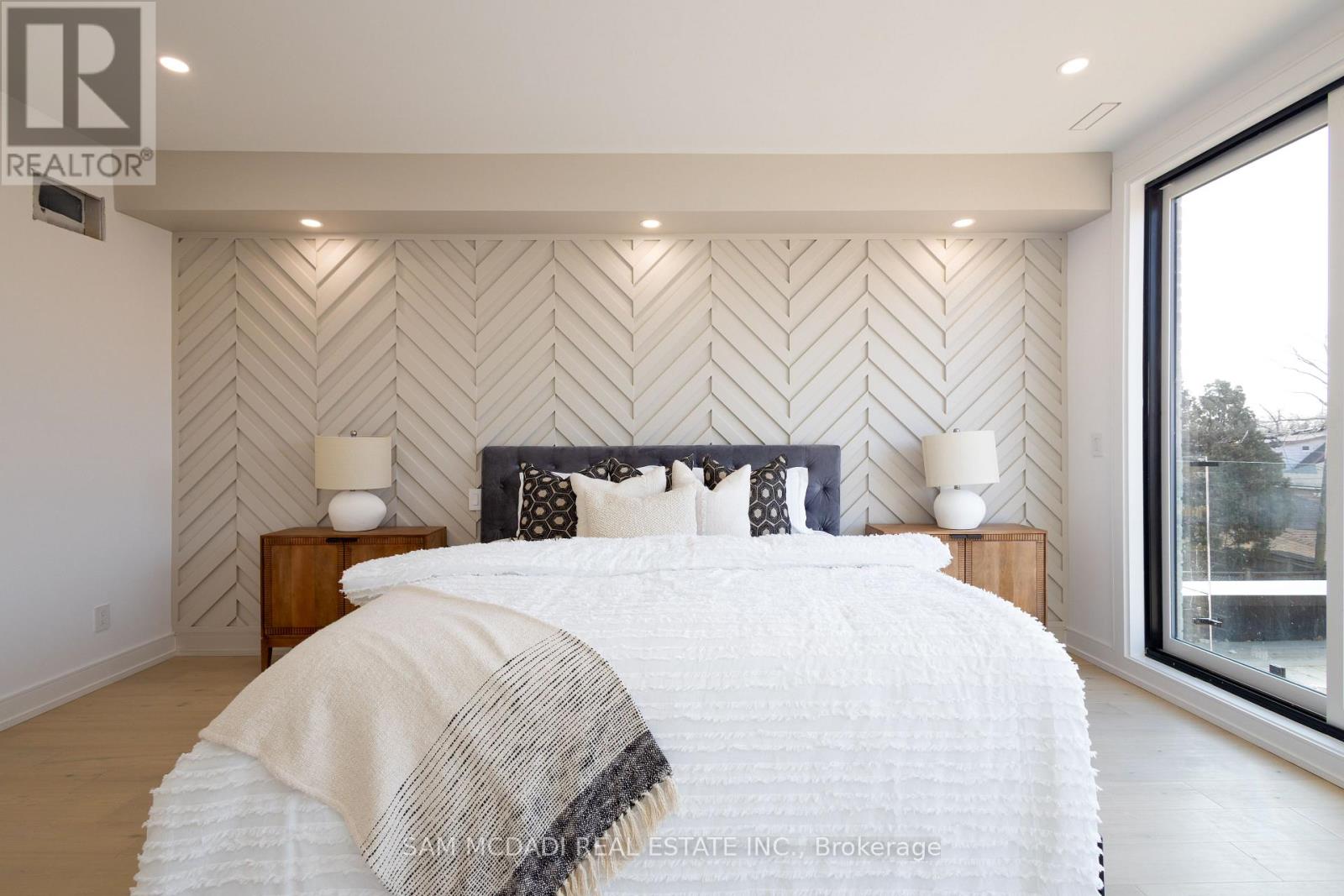 A bedroom with a large bed and a wall with a herringbone pattern.