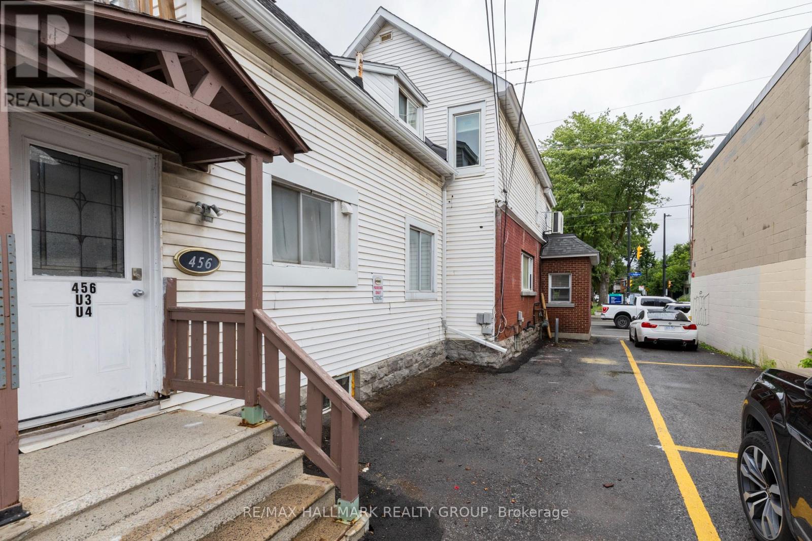 A white house with a brown door and a sign that says RE/MAX Hallmark Realty Group.