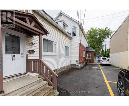 A white house with a brown door and a sign that says RE/MAX Hallmark Realty Group.