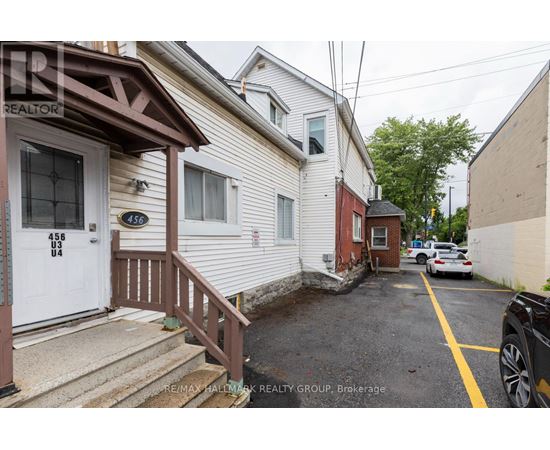 A white house with a brown door and a sign that says RE/MAX Hallmark Realty Group.