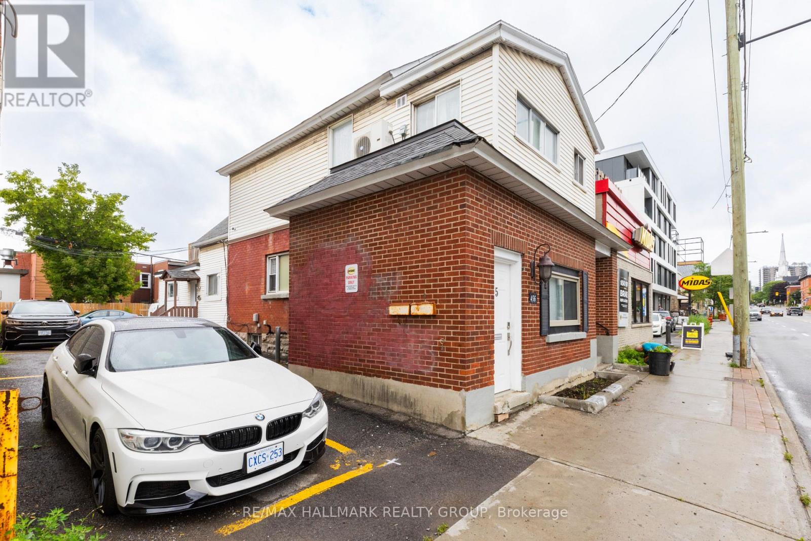 A white BMW is parked in front of a red brick building.