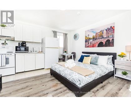 A bedroom with a bed, nightstand, and a painting on the wall.