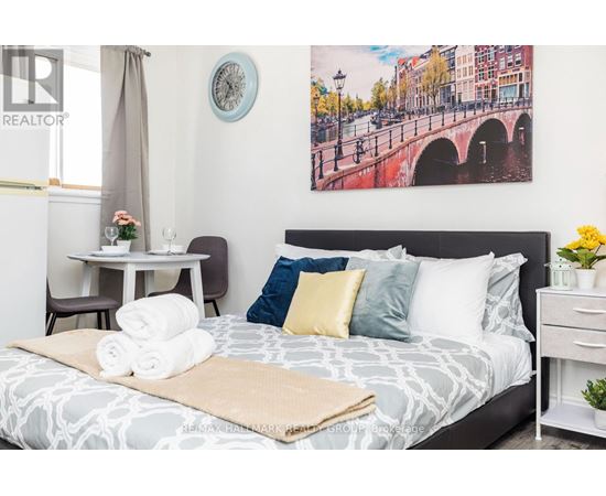 A bedroom with a large bed and a painting of a bridge on the wall.