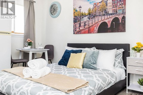 A bedroom with a large bed and a painting of a bridge on the wall.