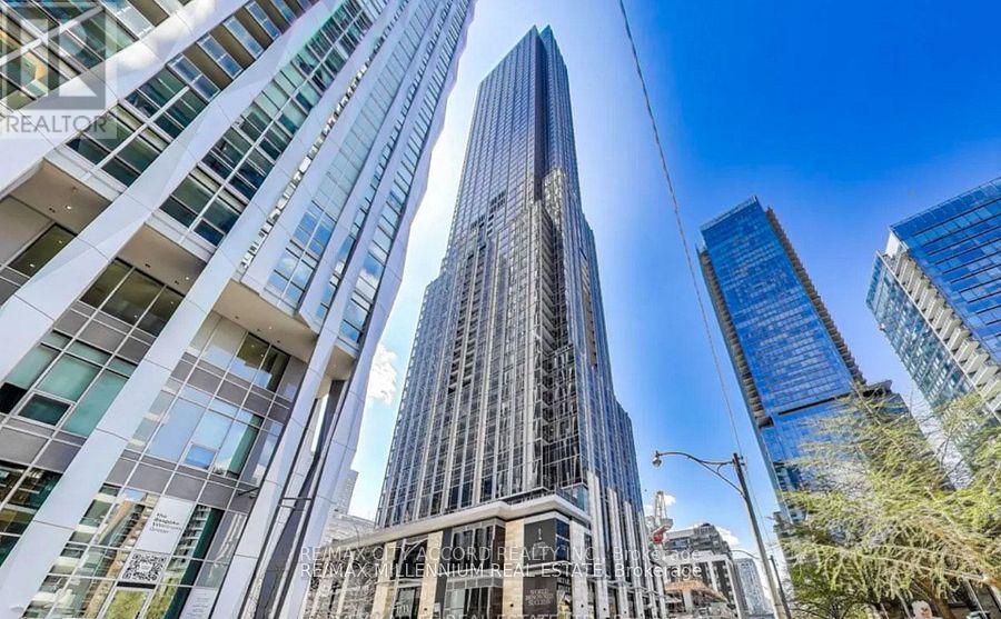 A tall building with a glass facade stands in the middle of a cityscape.