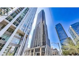 A tall building with a glass facade stands in the middle of a cityscape.