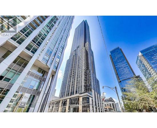 A tall building with a glass facade stands in the middle of a cityscape.