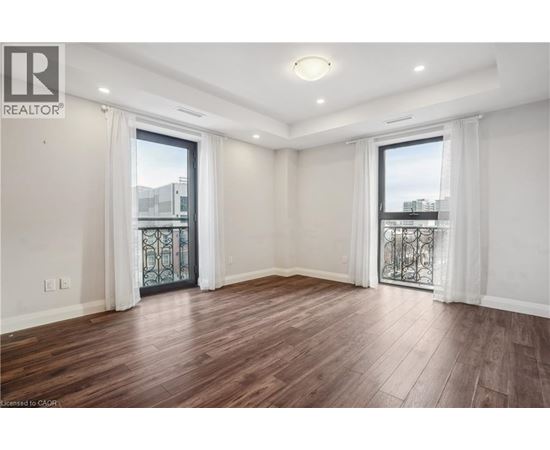 A spacious room with wooden flooring and white walls.