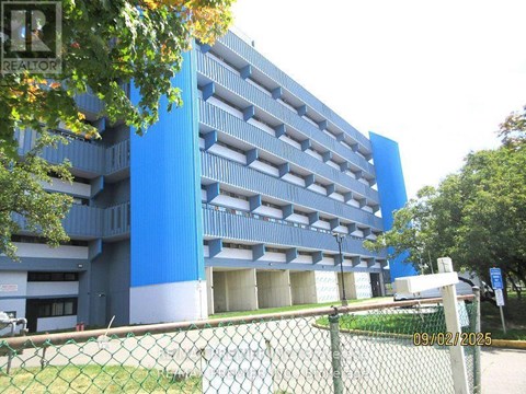 A blue parking garage with a fence in front.