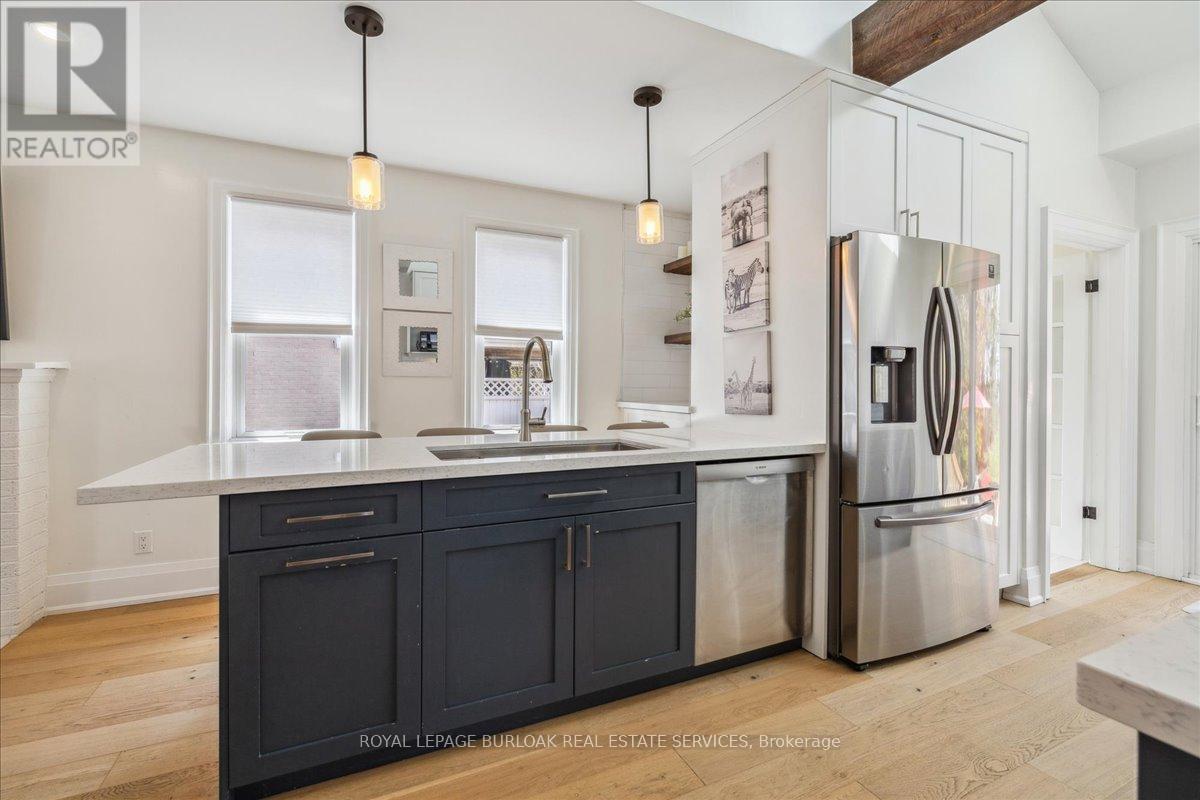A modern kitchen with dark cabinets and stainless steel appliances.