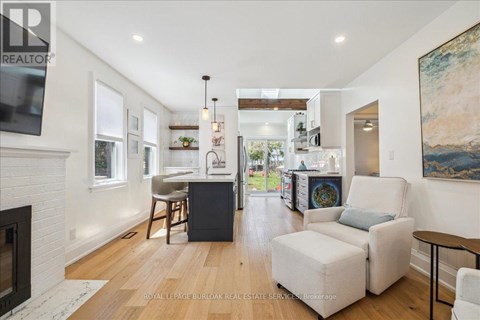 A well-lit, spacious living room with a fireplace and a painting on the wall.