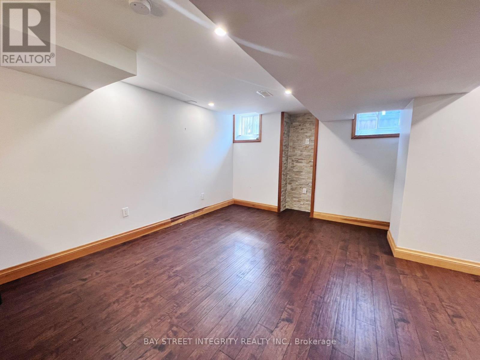 A room with wooden flooring and white walls, with a window and a door visible.