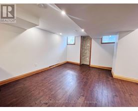 A room with wooden flooring and white walls, with a window and a door visible.