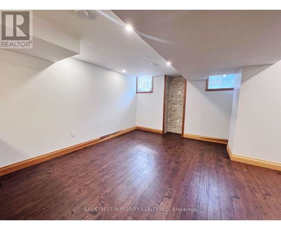 A room with wooden flooring and white walls, with a window and a door visible.