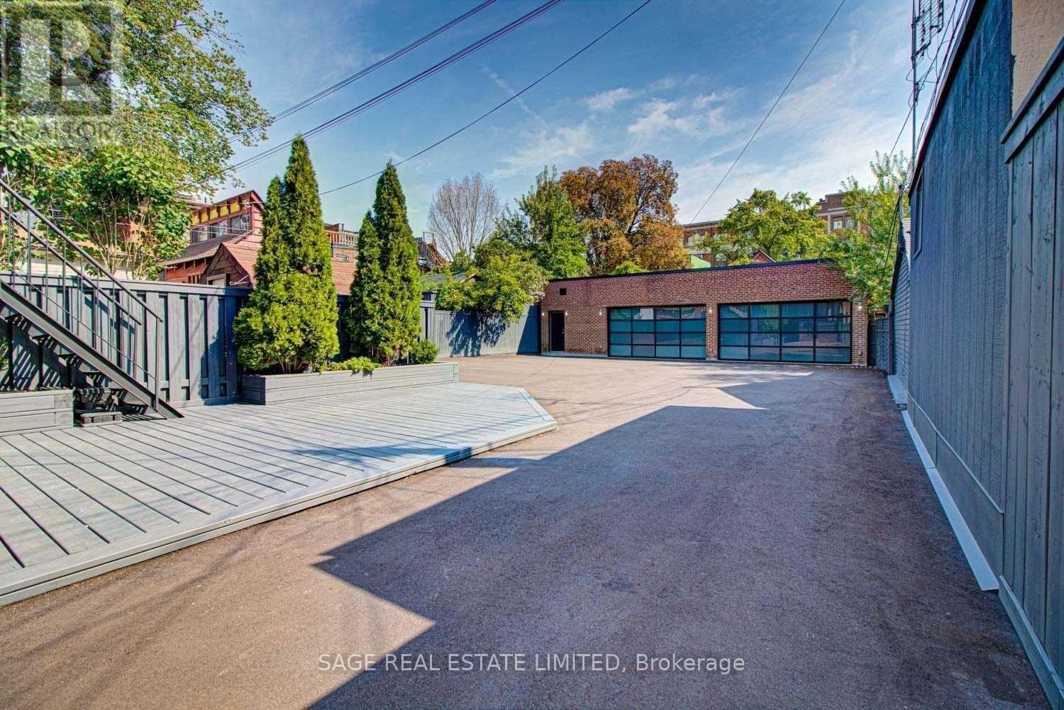 A large, empty driveway leads to a garage with a brick exterior.