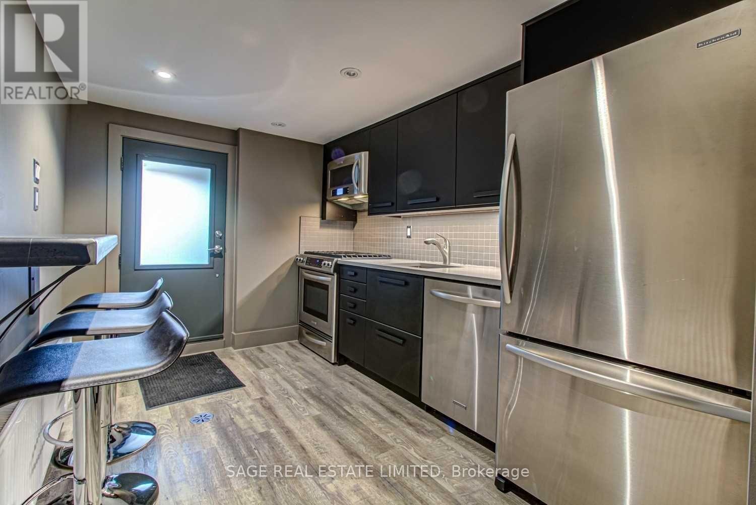 A modern kitchen with stainless steel appliances and black cabinets.