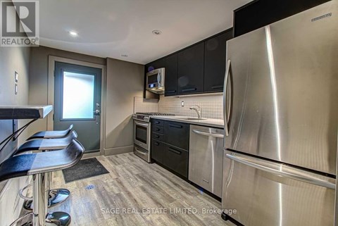 A modern kitchen with stainless steel appliances and black cabinets.
