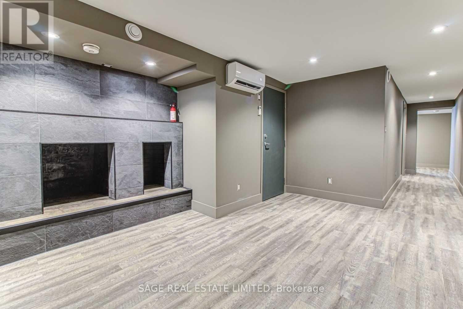 A spacious room with a fireplace and wood flooring.