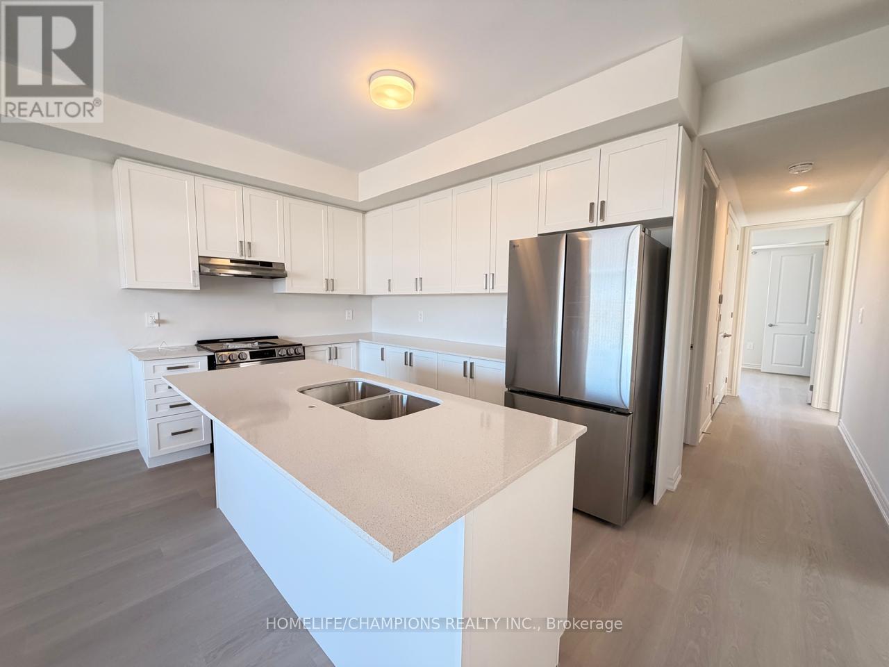 A kitchen with white cabinets and a stainless steel refrigerator.