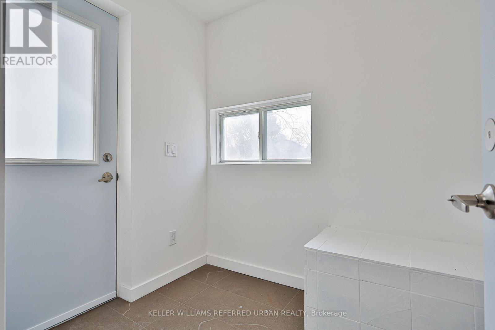 A room with a door, a window, and a white bench.