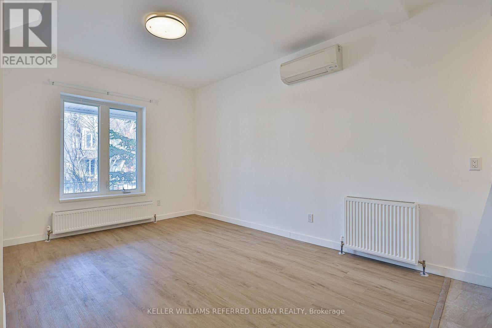A room with a window and a radiator on the floor.