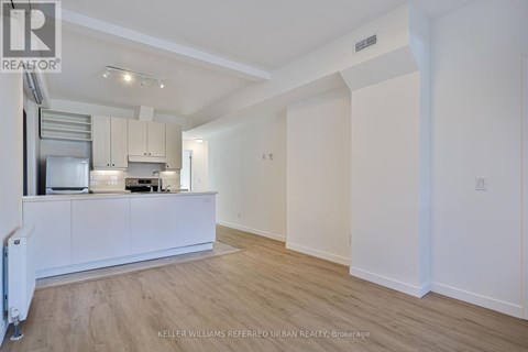A spacious kitchen with white cabinets and a wooden floor.