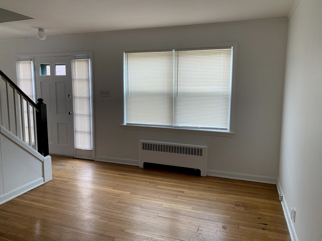 a living room with wood floors and a door and two windows