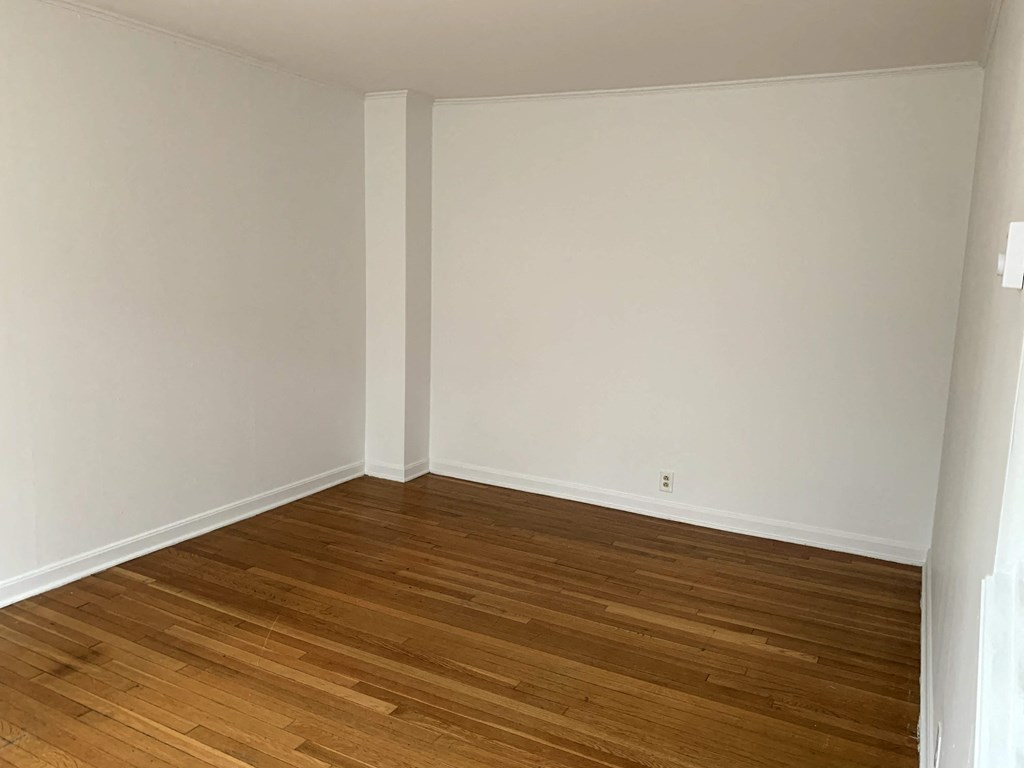 an empty room with wooden floors and white walls