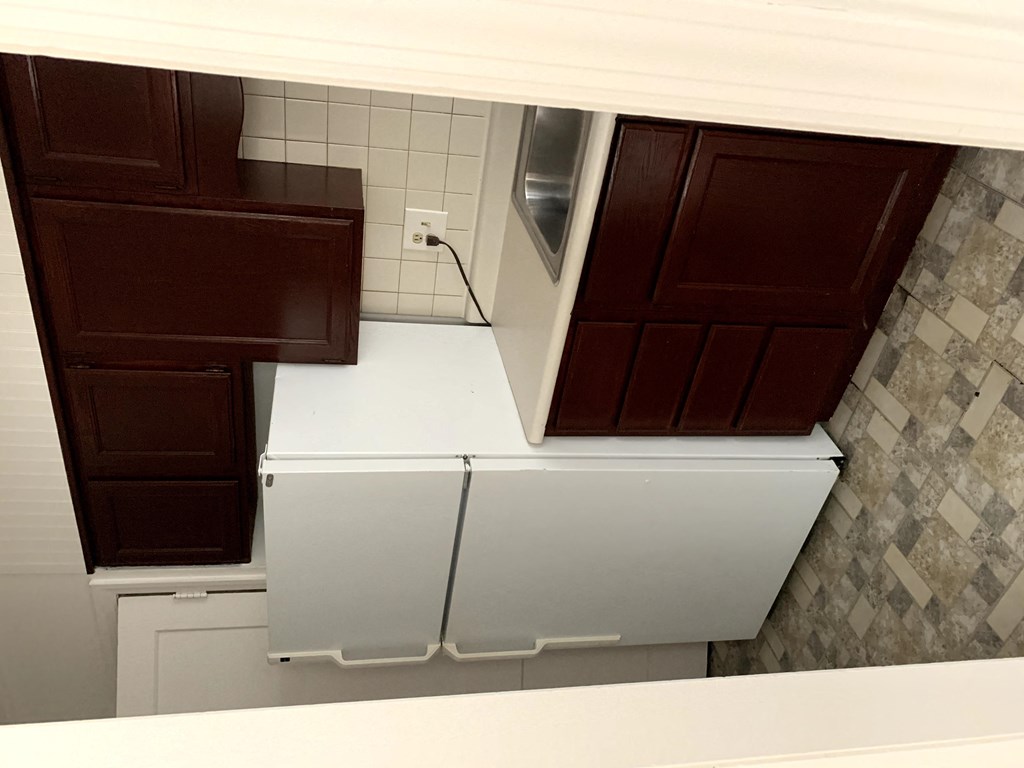 an overhead view of a kitchen with white counters and brown cabinets