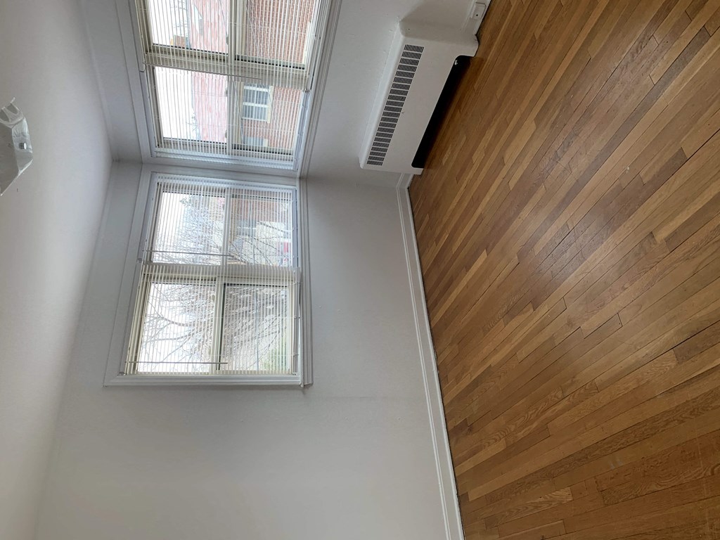 a view of a hallway with two windows and wood flooring
