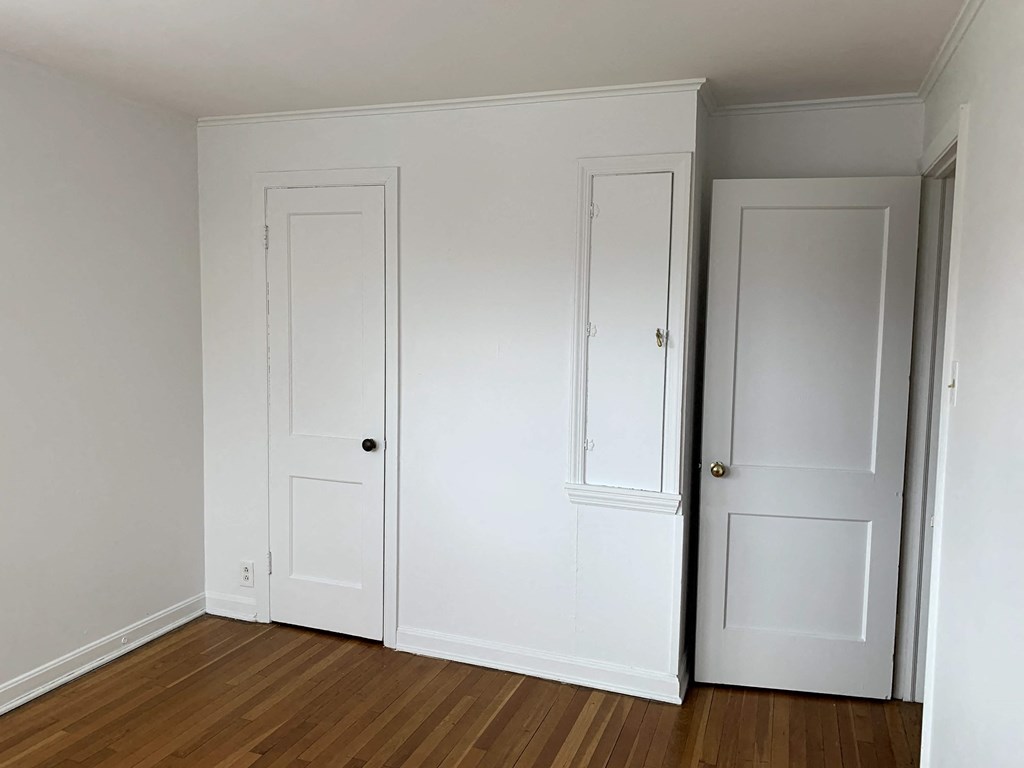 an empty room with white doors and a wooden floor