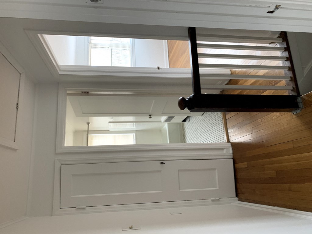 the view from the bottom of a stairwell looking up to a window with white