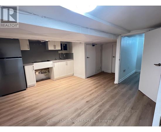 A kitchen area with a refrigerator, cabinets, and a microwave.