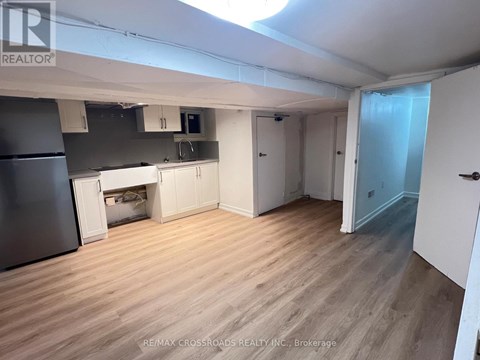 A kitchen area with a refrigerator, cabinets, and a microwave.