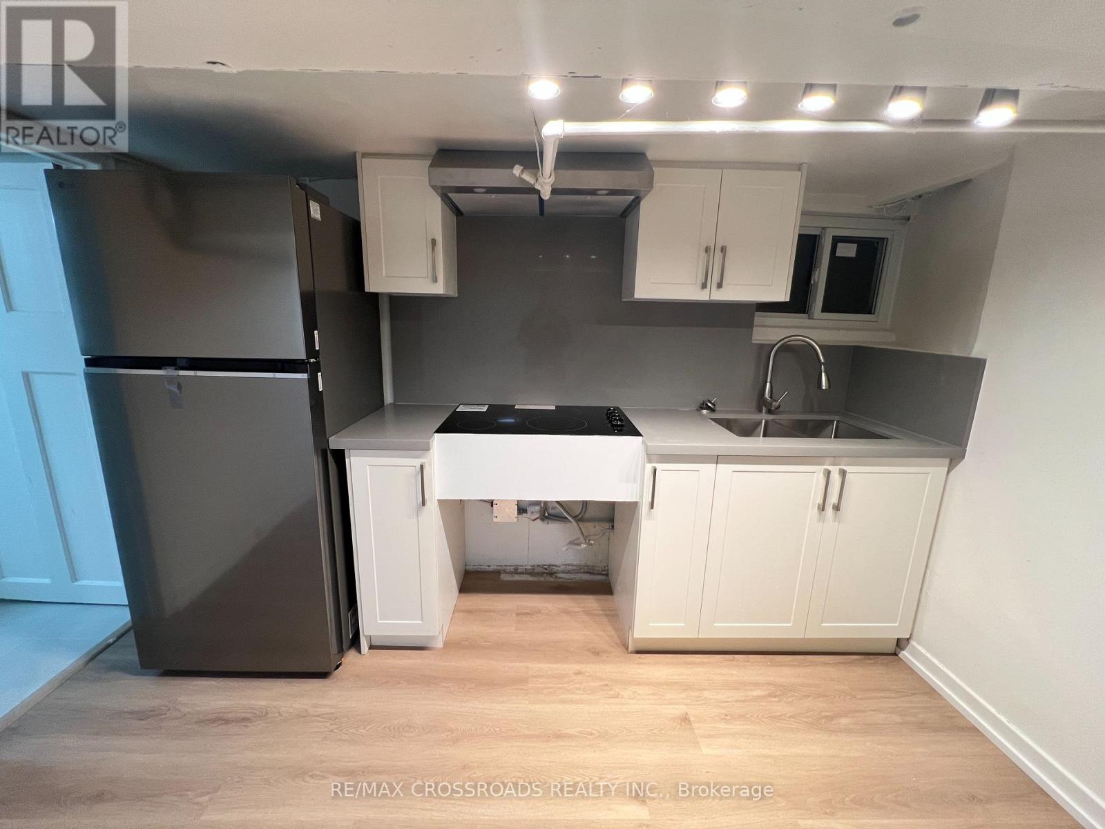 A kitchen with a black fridge, white cabinets, and a black countertop.