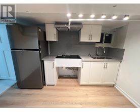 A kitchen with a black fridge, white cabinets, and a black countertop.