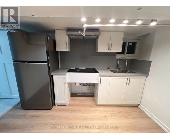 A kitchen with a black fridge, white cabinets, and a black countertop.