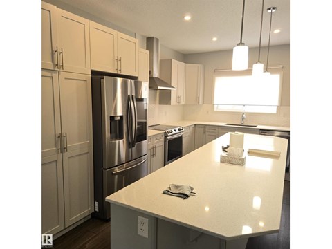 A kitchen with a white counter top and stainless steel appliances.