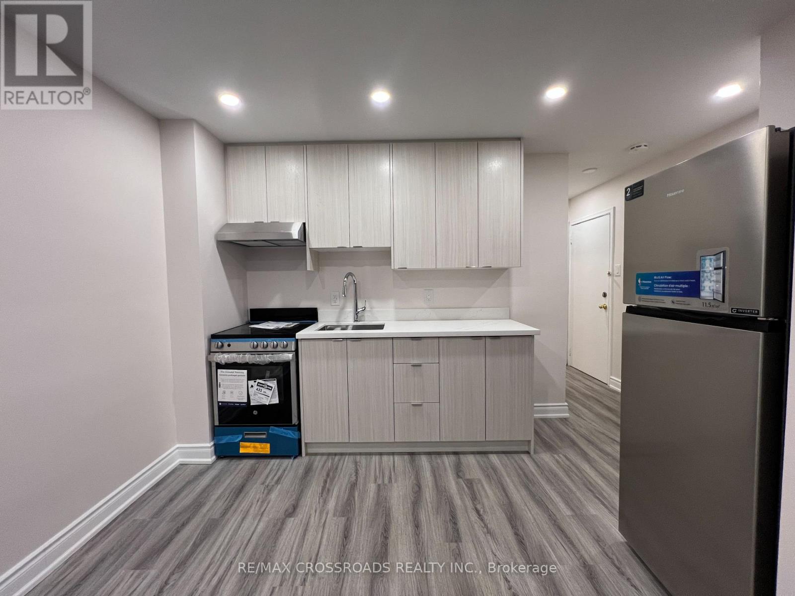 A kitchen area with a fridge, sink, and cabinets.