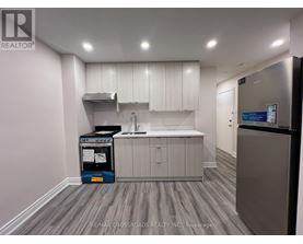 A kitchen area with a fridge, sink, and cabinets.