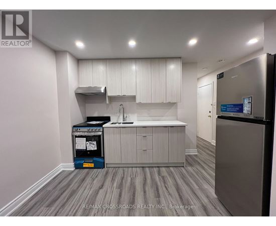 A kitchen area with a fridge, sink, and cabinets.