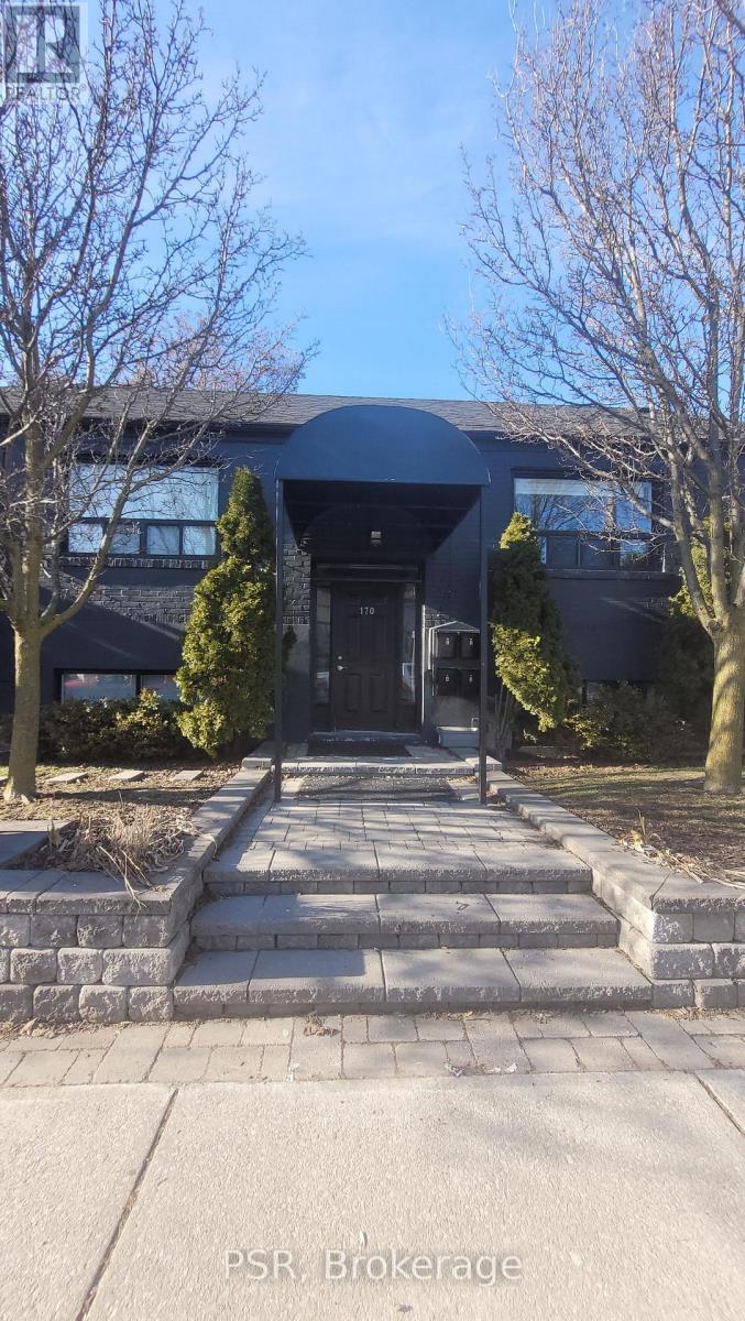 The image shows a modern building with a dark facade and a stone entrance.