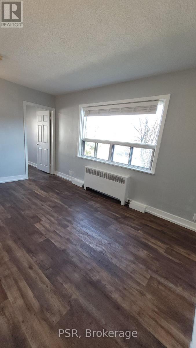 A room with wood flooring and a window with a white frame.