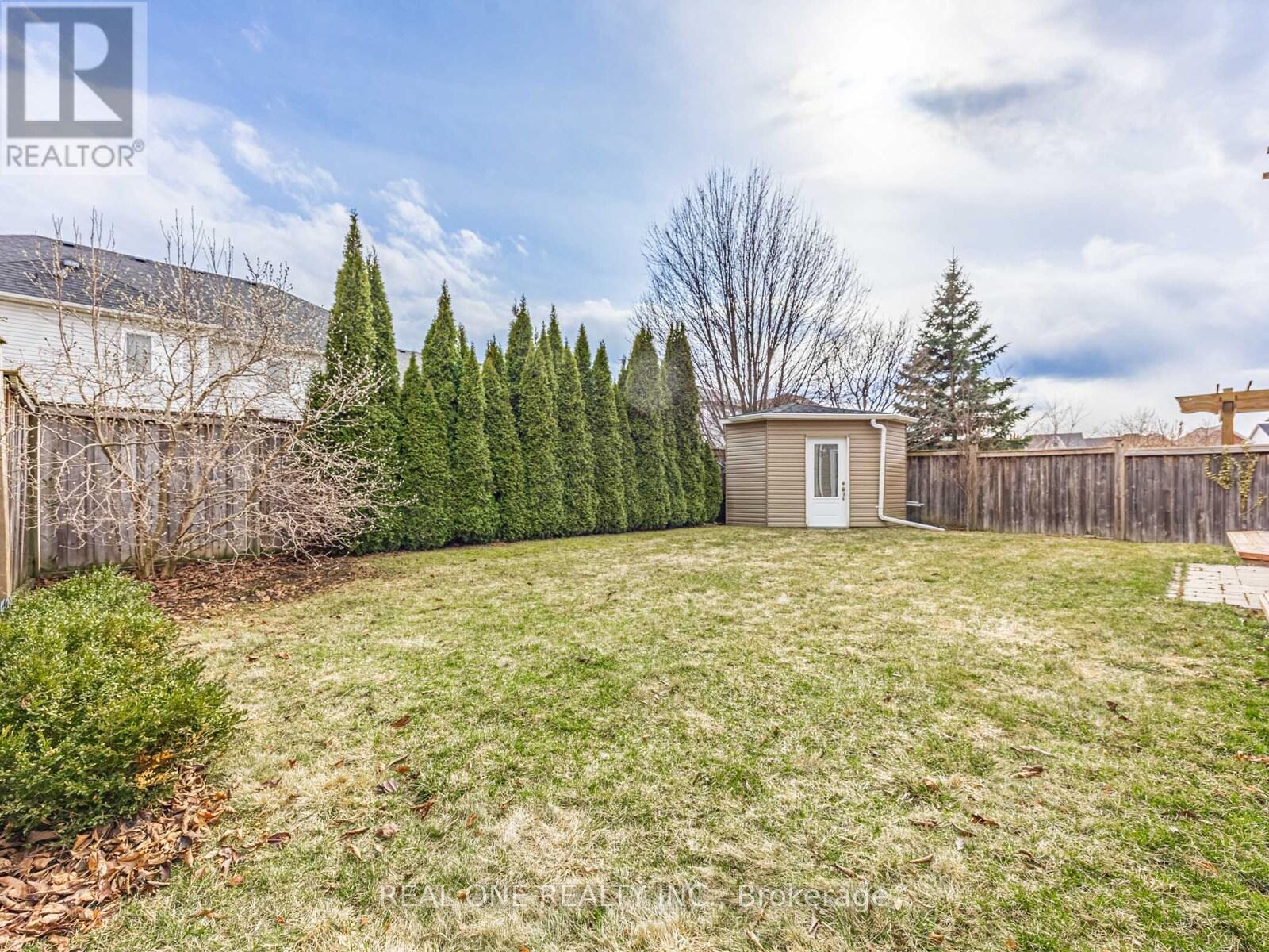 A backyard with a fence, a shed, and a row of trees.