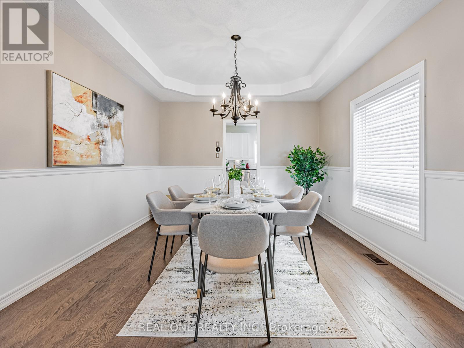 A dining room with a chandelier, a table with chairs, and a rug on the floor.